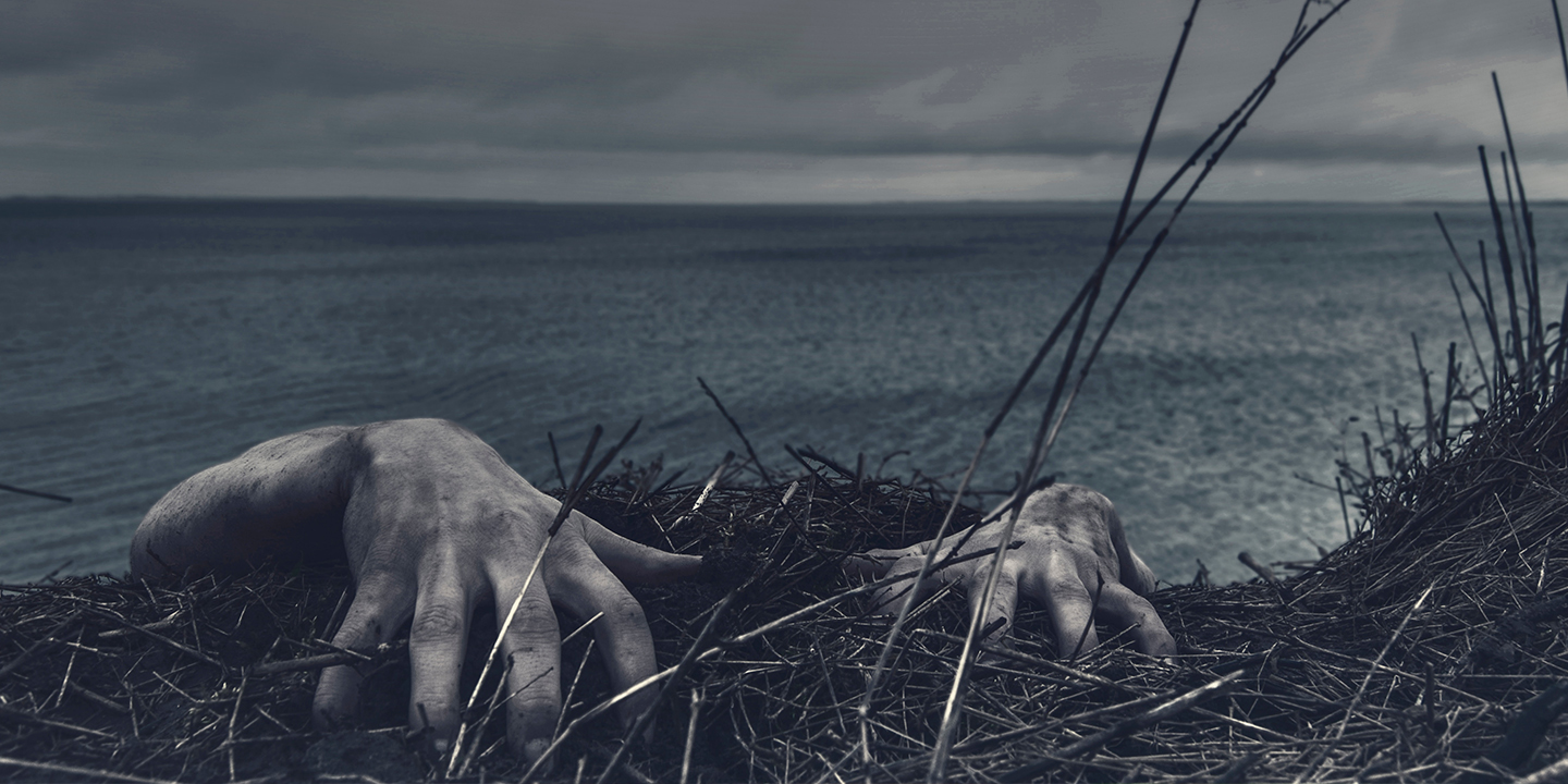 Zombiehänder i strandbrynet av vattnet.